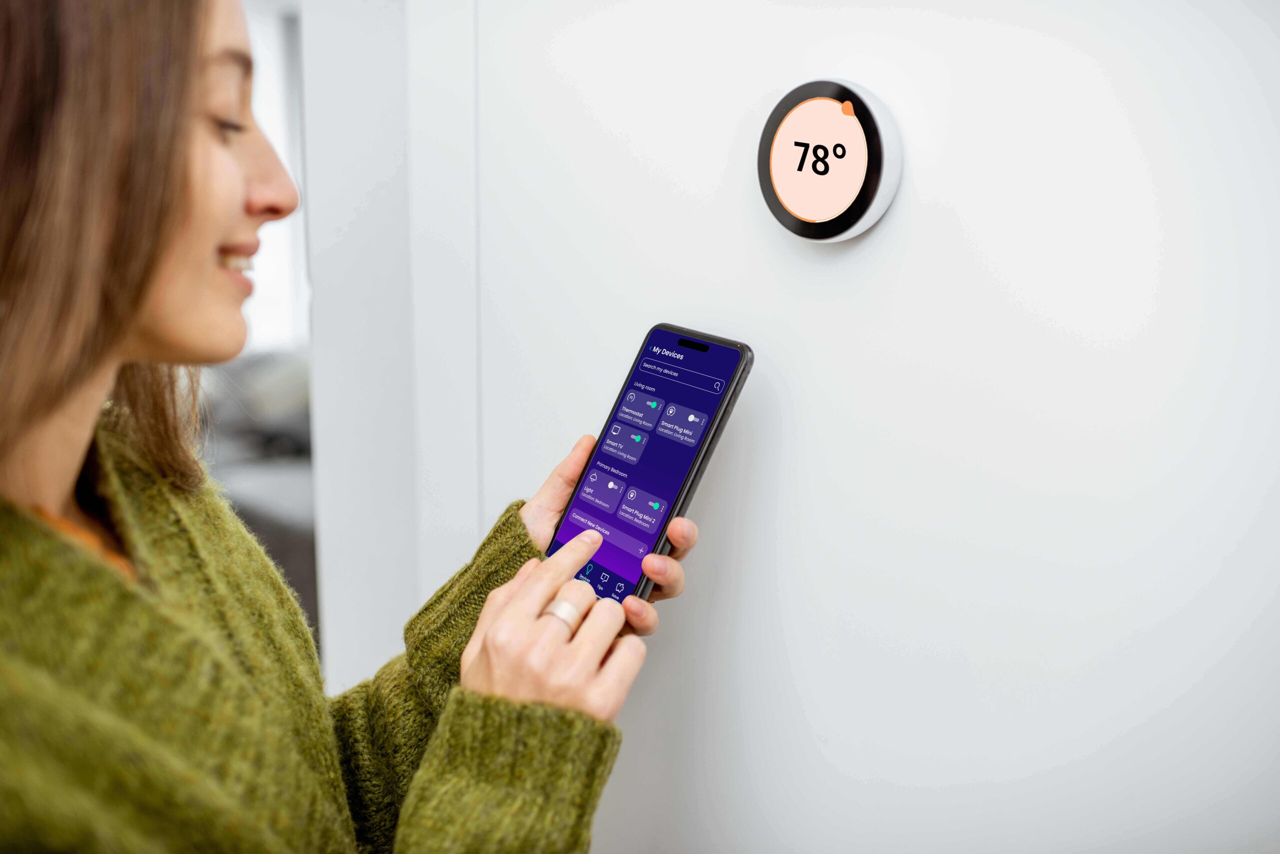 Woman-with-Phone-78 Woman with smart phone screen and smart thermostat set to 78 degrees.
